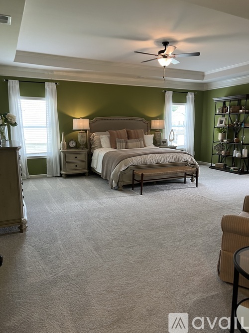 A bedroom with a large bed and a ceiling fan.