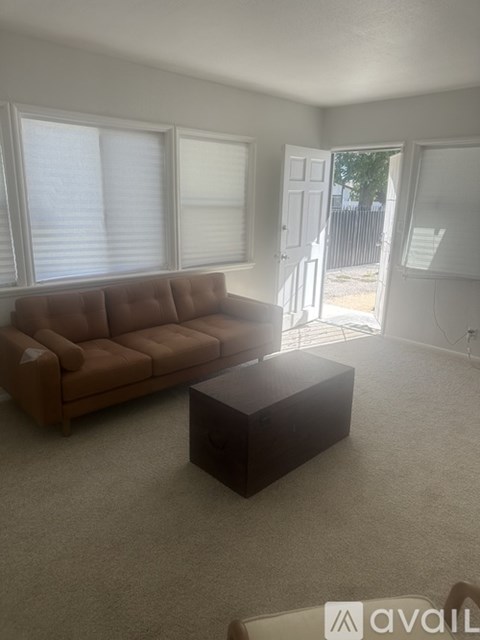 A brown couch sits in a living room with a carpeted floor and a coffee table.