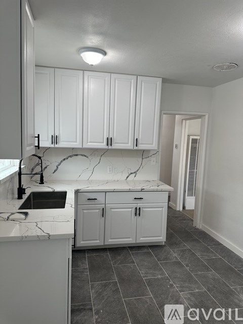A kitchen with white cabinets and marble countertops.