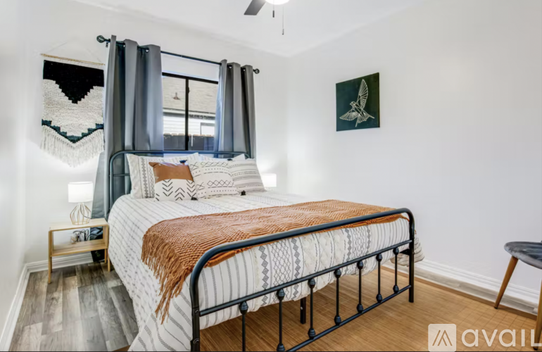 A bedroom with a large bed and a window with curtains.