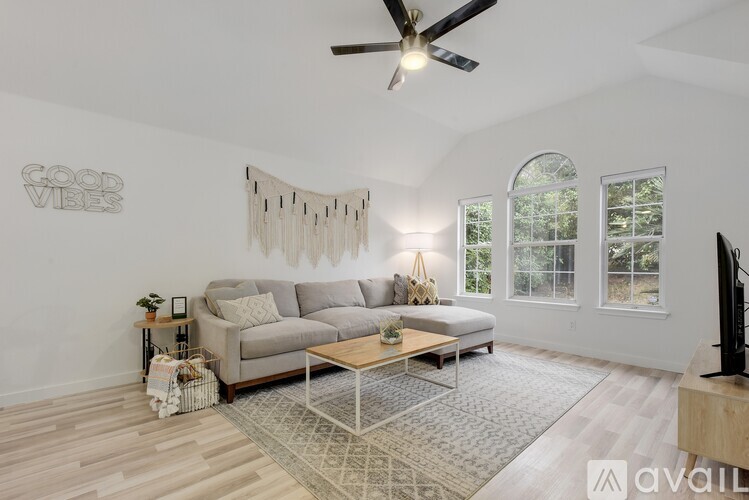 A living room with a grey couch, a wooden coffee table, and a ceiling fan.