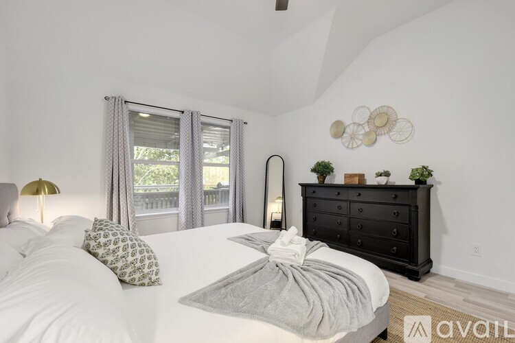 A bedroom with a large bed and a dresser with a mirror above it.