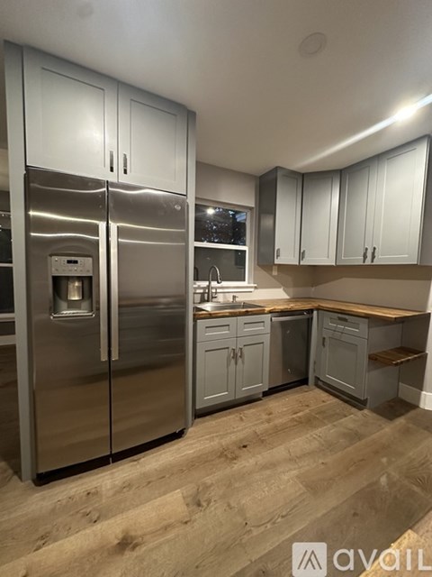 A kitchen with a stainless steel refrigerator and wooden countertops.