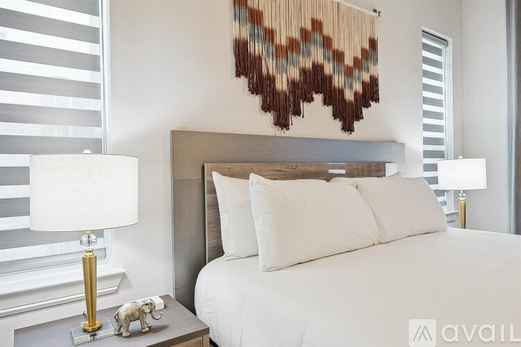 A bedroom with a white bed and a lamp on a side table.
