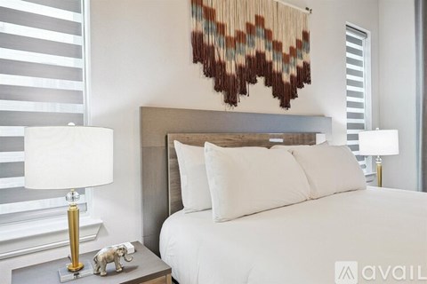 A bedroom with a white bed and a lamp on a side table.