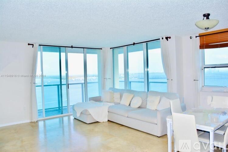 A white living room with a view of the ocean.