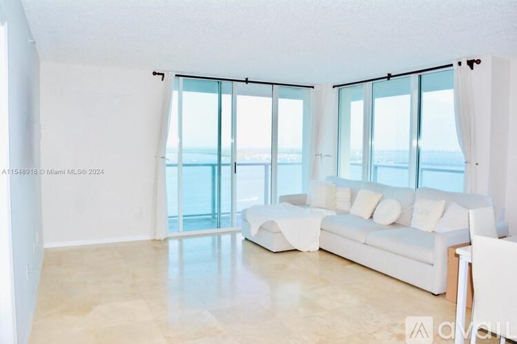 A spacious living room with a large window overlooking the sea.