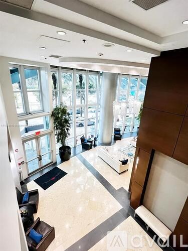 A view of a lobby with a plant and a bench.