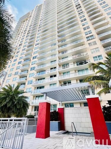 A tall residential building with balconies and a red sculpture in front.