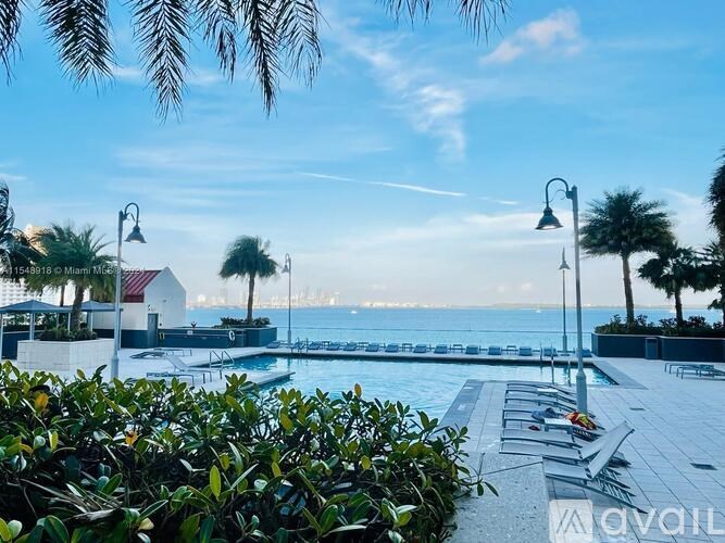 A pool area with a view of the sea and palm trees.