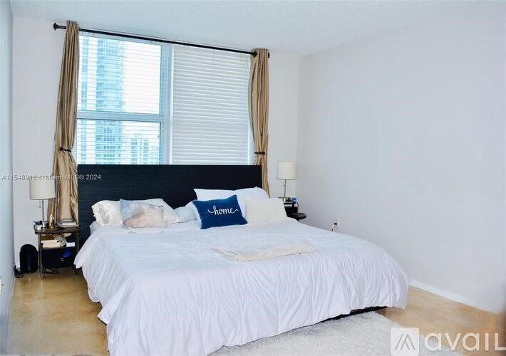 A bedroom with a large bed and a window with curtains.