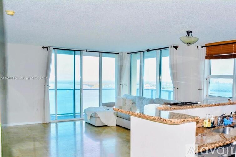 A spacious living room with a kitchen area and a view of the water.