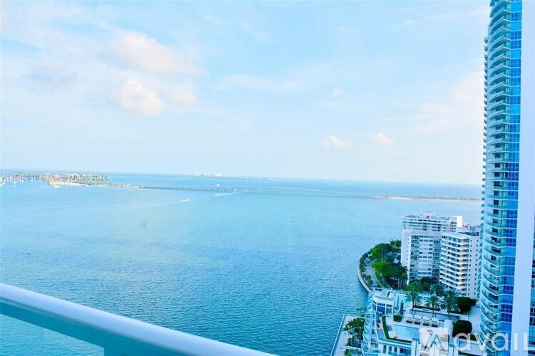 A view from a high-rise building overlooking a calm body of water with a clear sky above.
