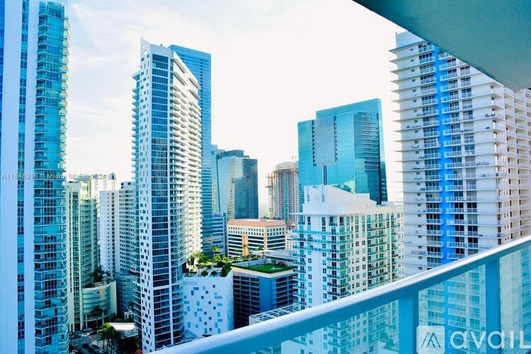 A cityscape with tall buildings and a balcony in the foreground.