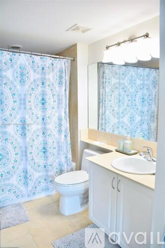 A bathroom with a toilet, sink, and shower curtain.