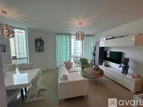A living room with white furniture and a flat screen TV.