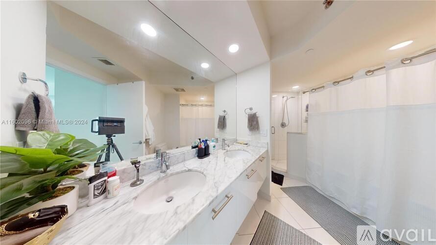 A bathroom with a white countertop and a shower with a white curtain.