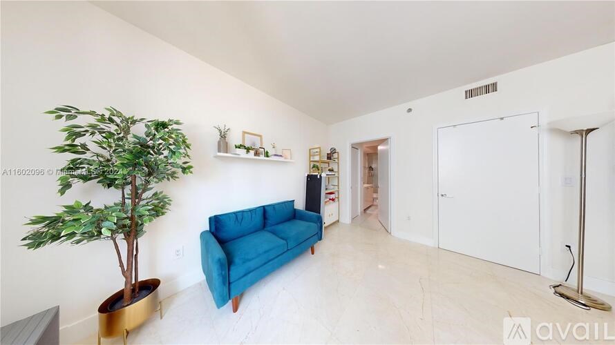 A living room with a blue couch and a plant.