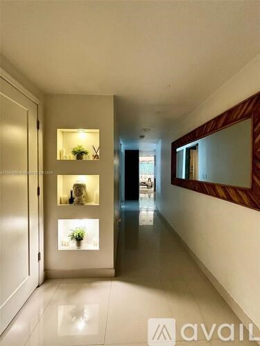 A hallway with a mirror on the wall and a plant in a window.