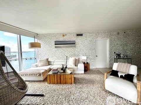 A living room with white furniture and a large window overlooking the water.