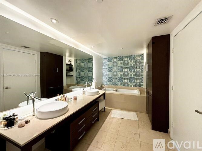 A bathroom with a large mirror, two sinks, and a bathtub.
