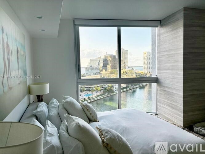 A bedroom with a large bed and a view of the city through the window.