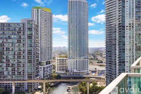 A cityscape with tall buildings and a river in the foreground.
