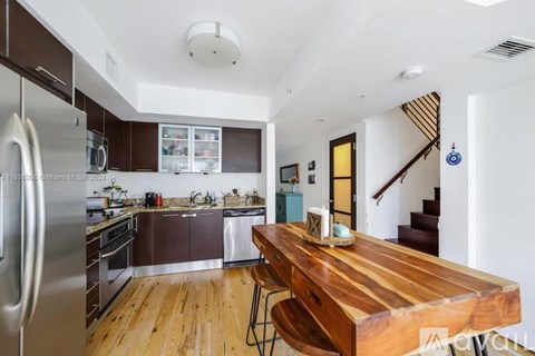 A kitchen with a wooden table and stainless steel appliances.