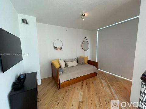 A bedroom with a bed, a television, and a wooden floor.