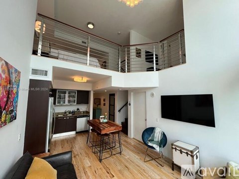 A living room with a black leather couch and a wooden table.