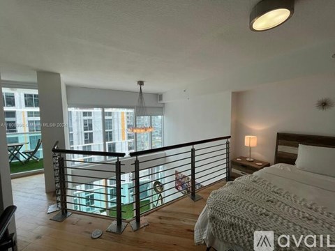 A bedroom with a large bed and a balcony with a glass railing.
