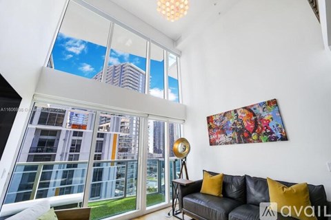 A living room with a couch and a large window overlooking a cityscape.