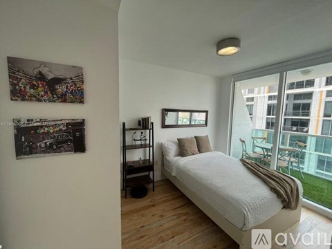 A bedroom with a large bed, a bookshelf, and two framed pictures on the wall.
