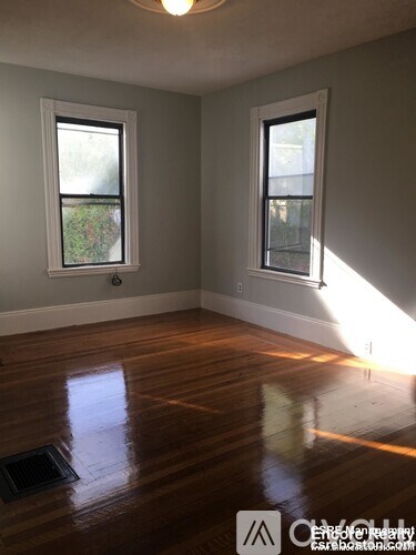 A room with wooden floors and two windows.