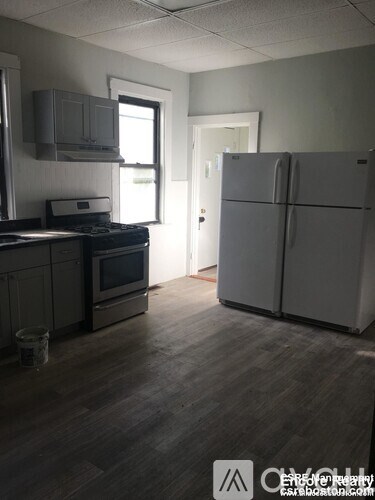 A kitchen with a refrigerator and a stove top oven.