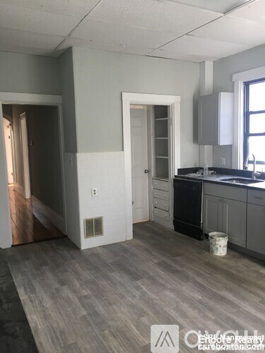 A kitchen with a black dishwasher and a white door.