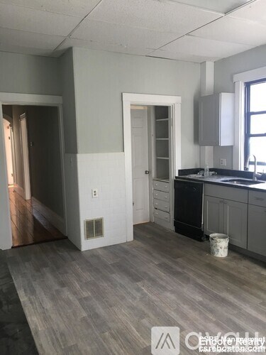 A kitchen with a black dishwasher and a white door.