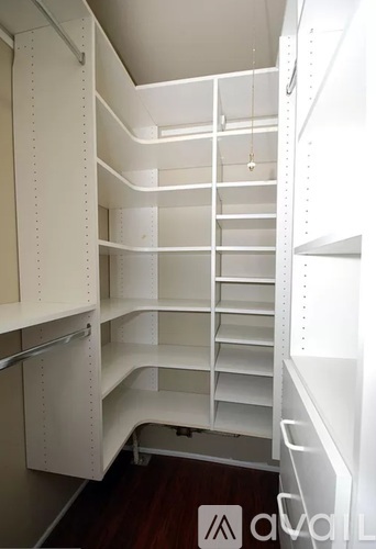 A white walk in closet with shelves and drawers.