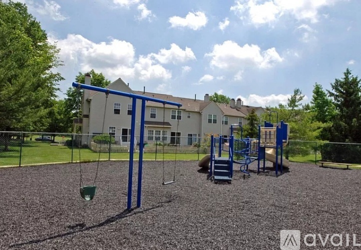A playground with a swing set and a building in the background.