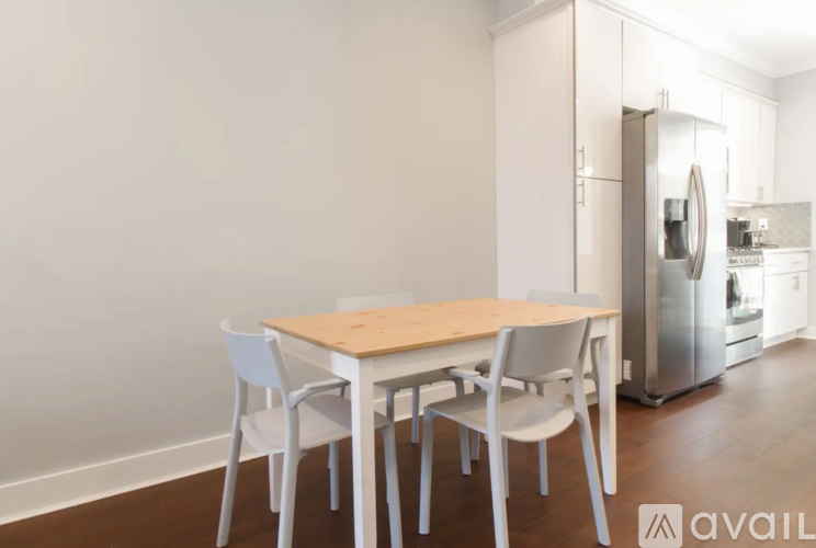 A kitchen with a table and chairs in the foreground and a refrigerator in the background.