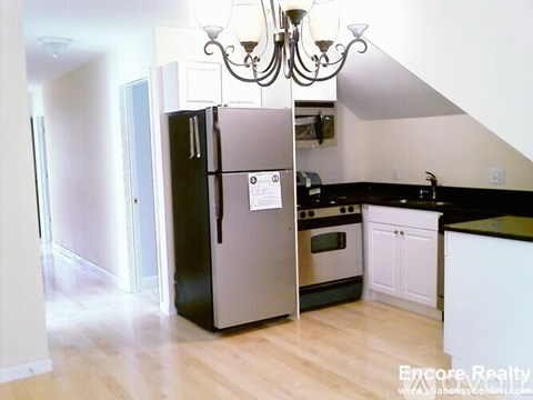 A kitchen with a black fridge and a chandelier.