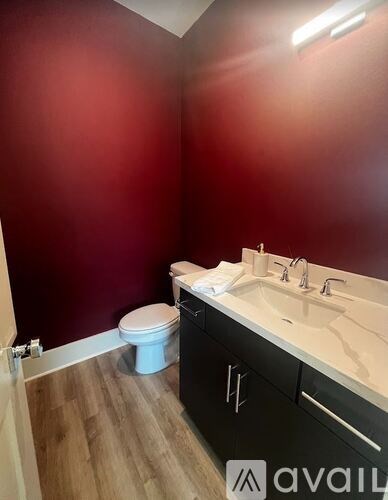 A bathroom with a toilet, sink, and wooden floor.