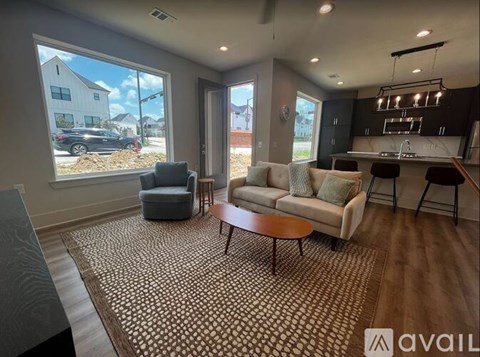 A living room with a large window, a sofa, a chair, and a coffee table.