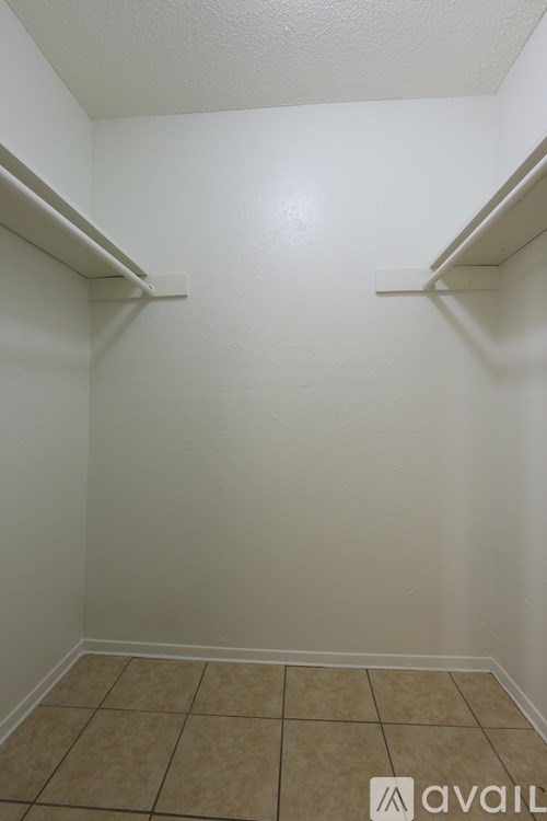 A white wall with a shelf and tiled floor.