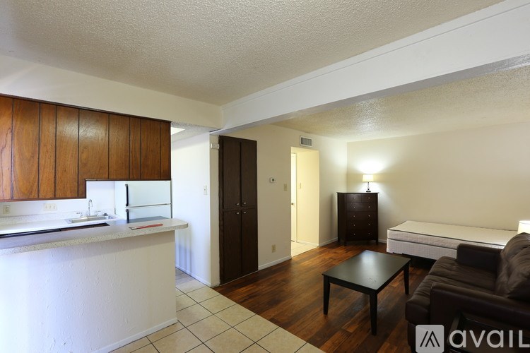 A living room with a couch, a coffee table, and a kitchen area with a sink and cabinets.