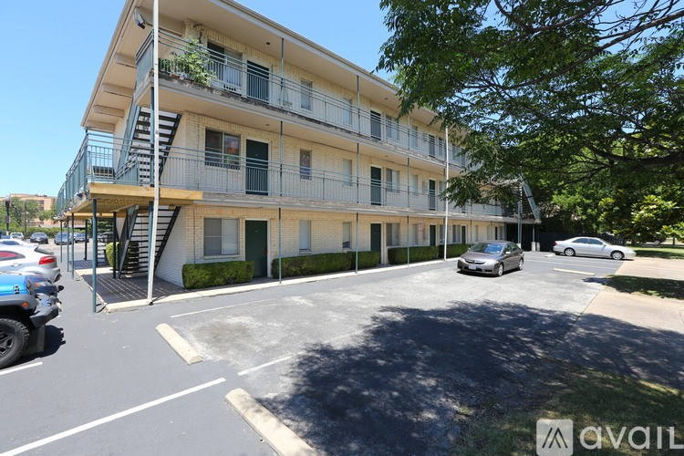 A parking lot in front of a multi-story apartment building with cars parked.