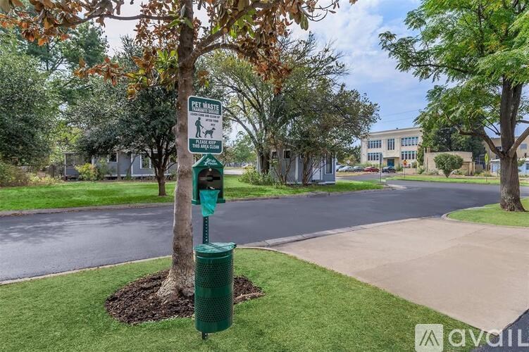A sign for a pet waste area is located next to a green trash can.