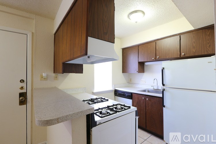 A kitchen with a white stove and wooden cabinets.