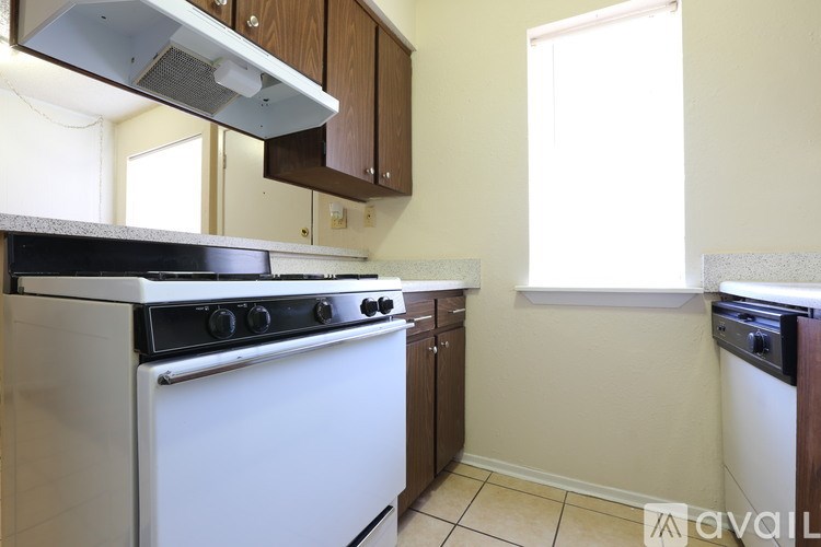 A kitchen with a white stove top oven and wooden cabinets.