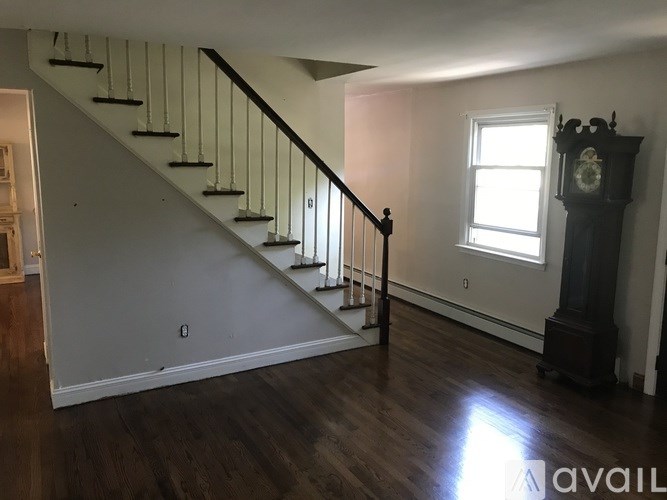 A living room with a staircase and a grandfather clock.